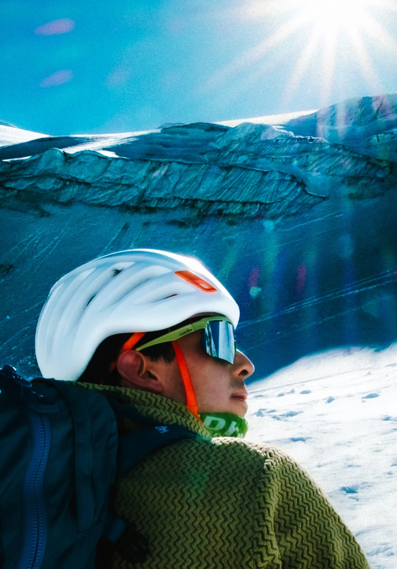 Mountaineer in a white helmet beneath a sunlit glacier