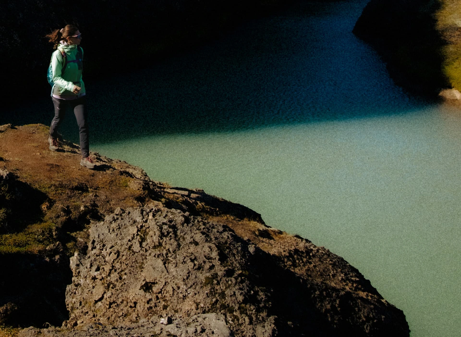 Hiker looking out over a turquoise glacial lake