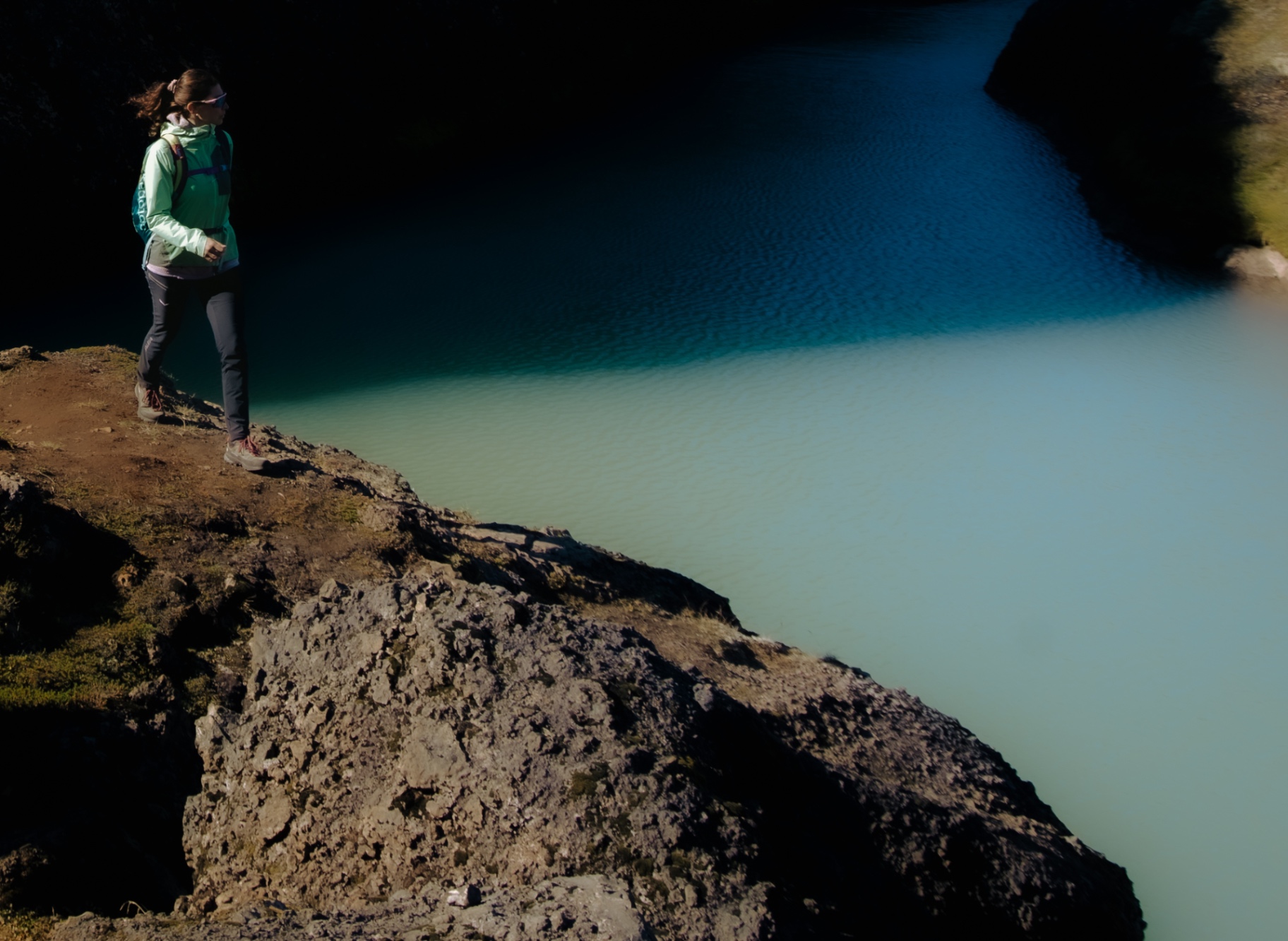 Hiker looking out over a turquoise glacial lake