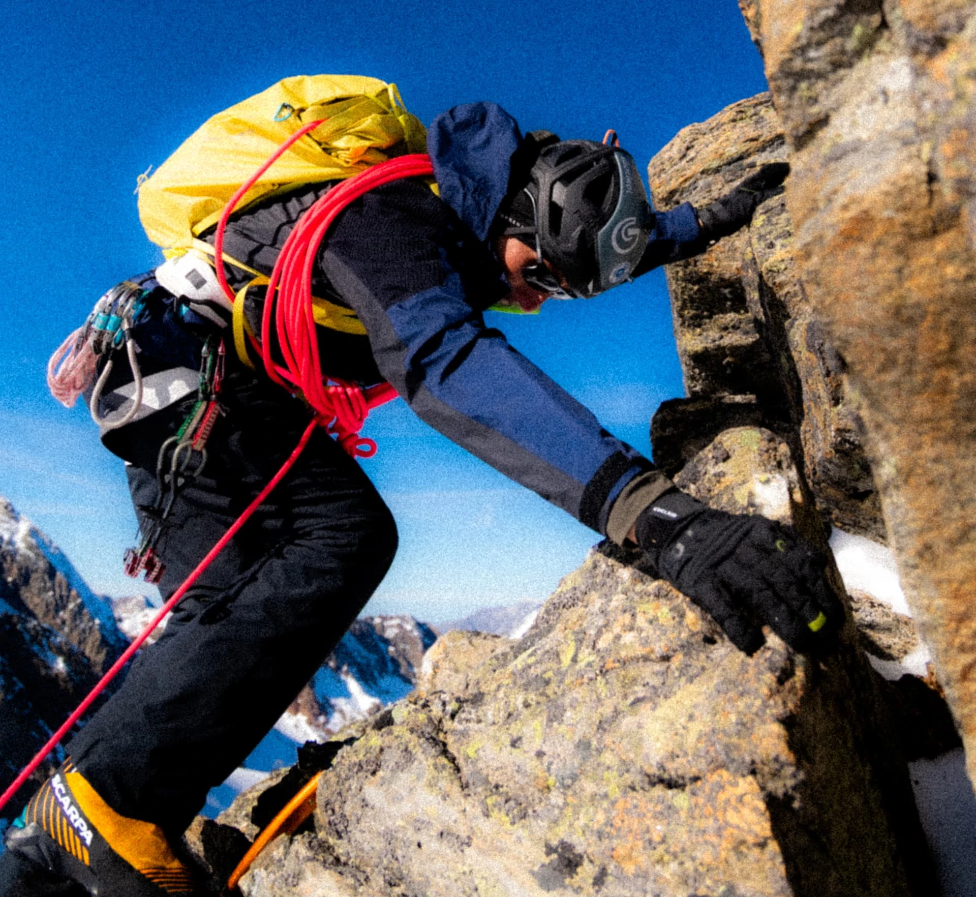 Alpinist climbing a rocky ridge with a red rope