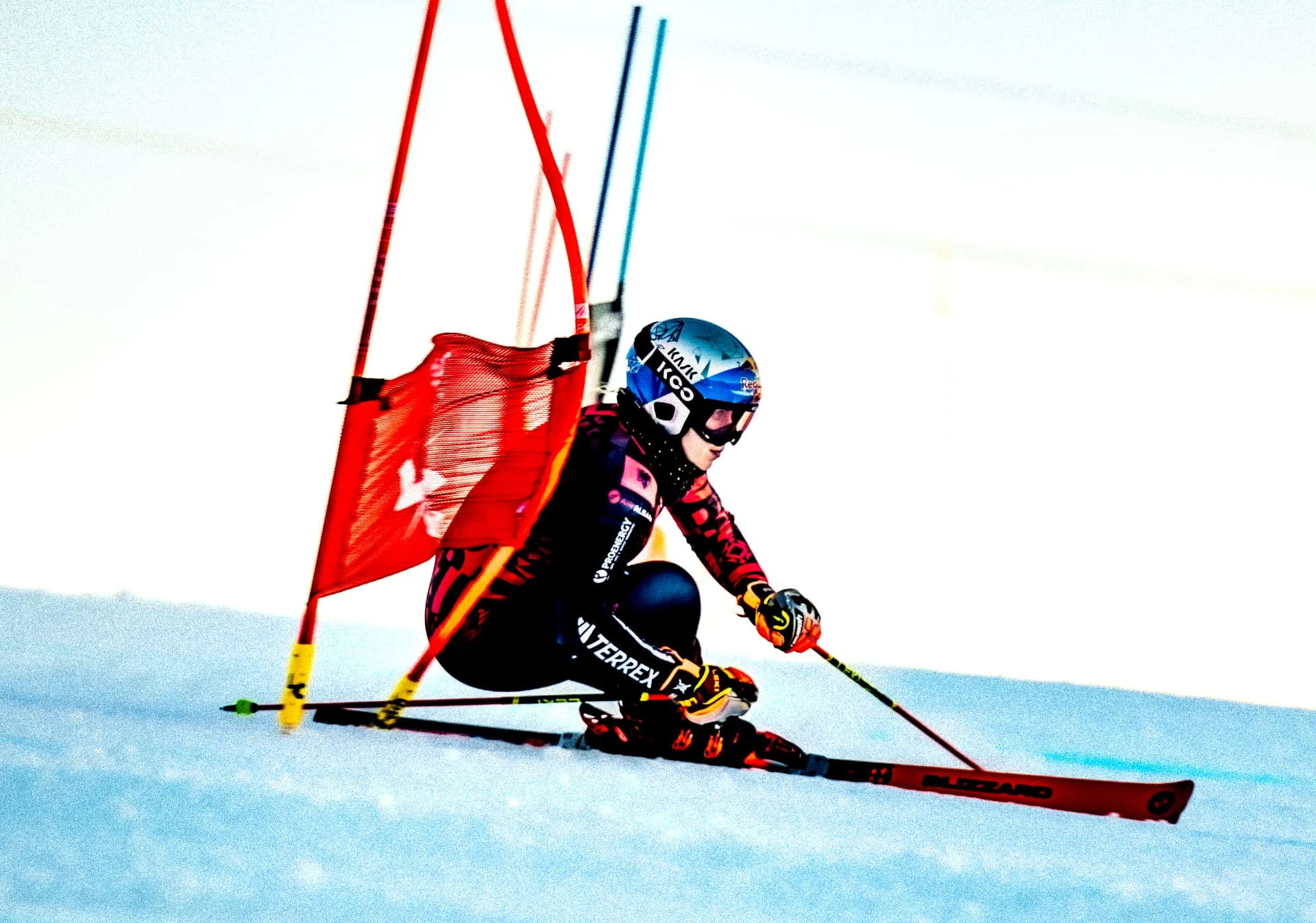 Ski racer leaning into a red gate at full speed