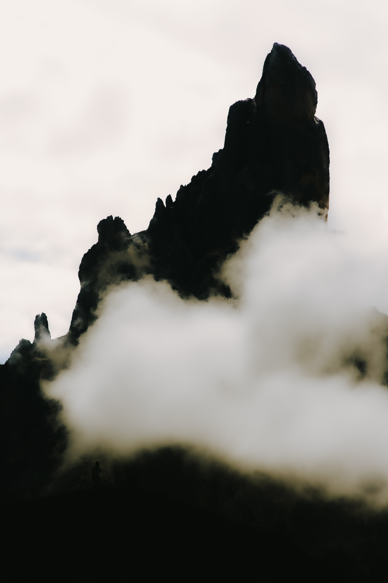 Dark rock spire emerging among the clouds