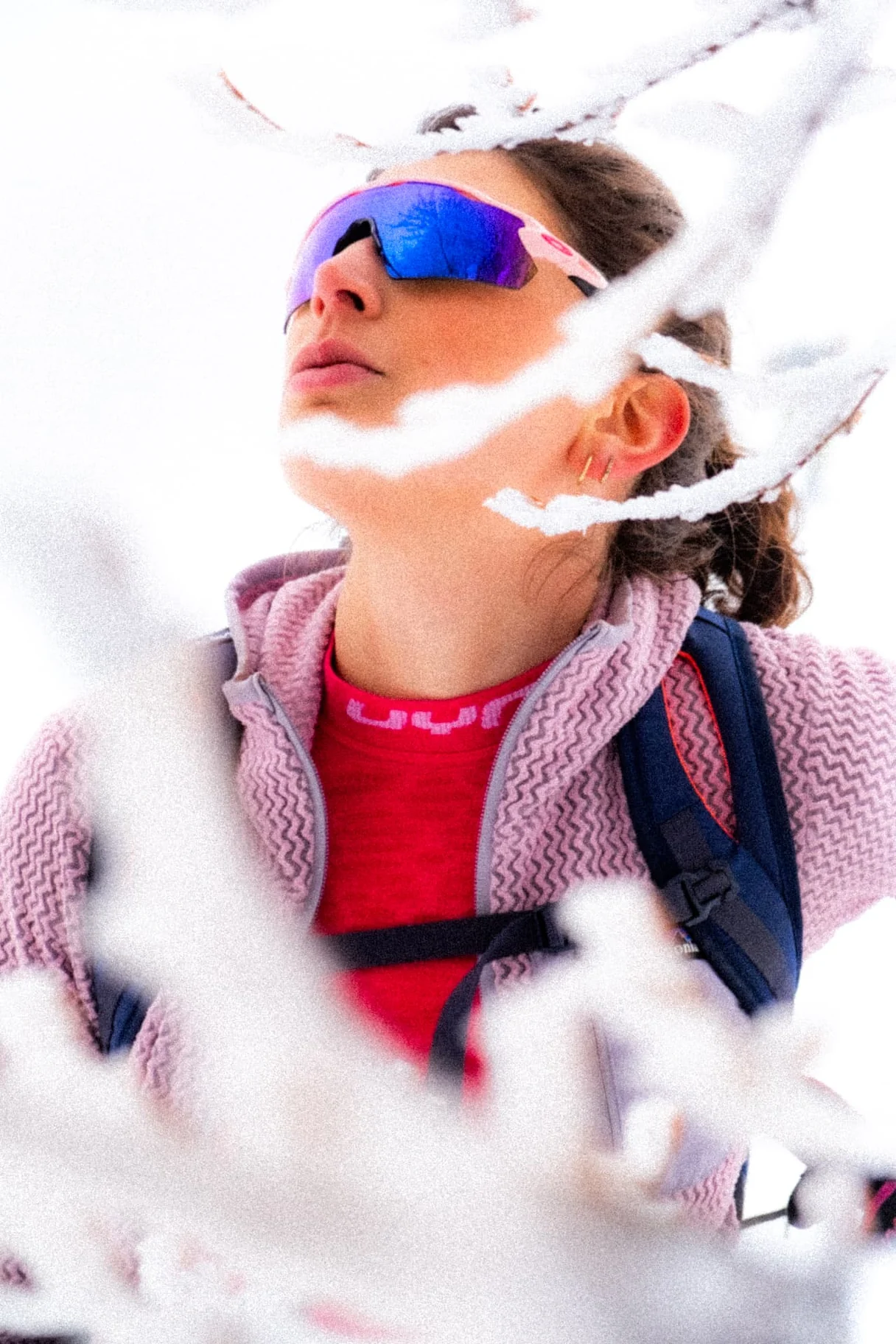 Ski tourer with mirrored sunglasses framed by snow-covered branches