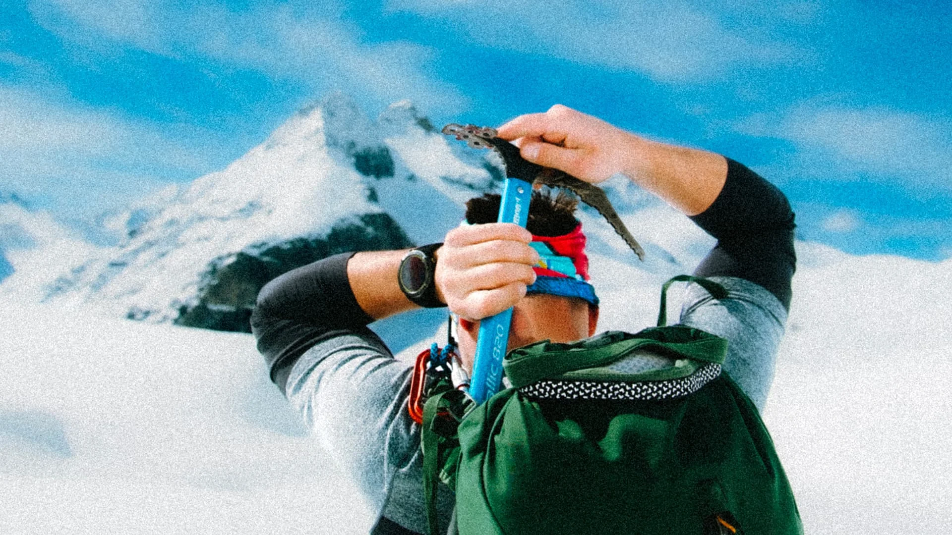 Mountaineer carrying an ice axe with a snowy peak behind