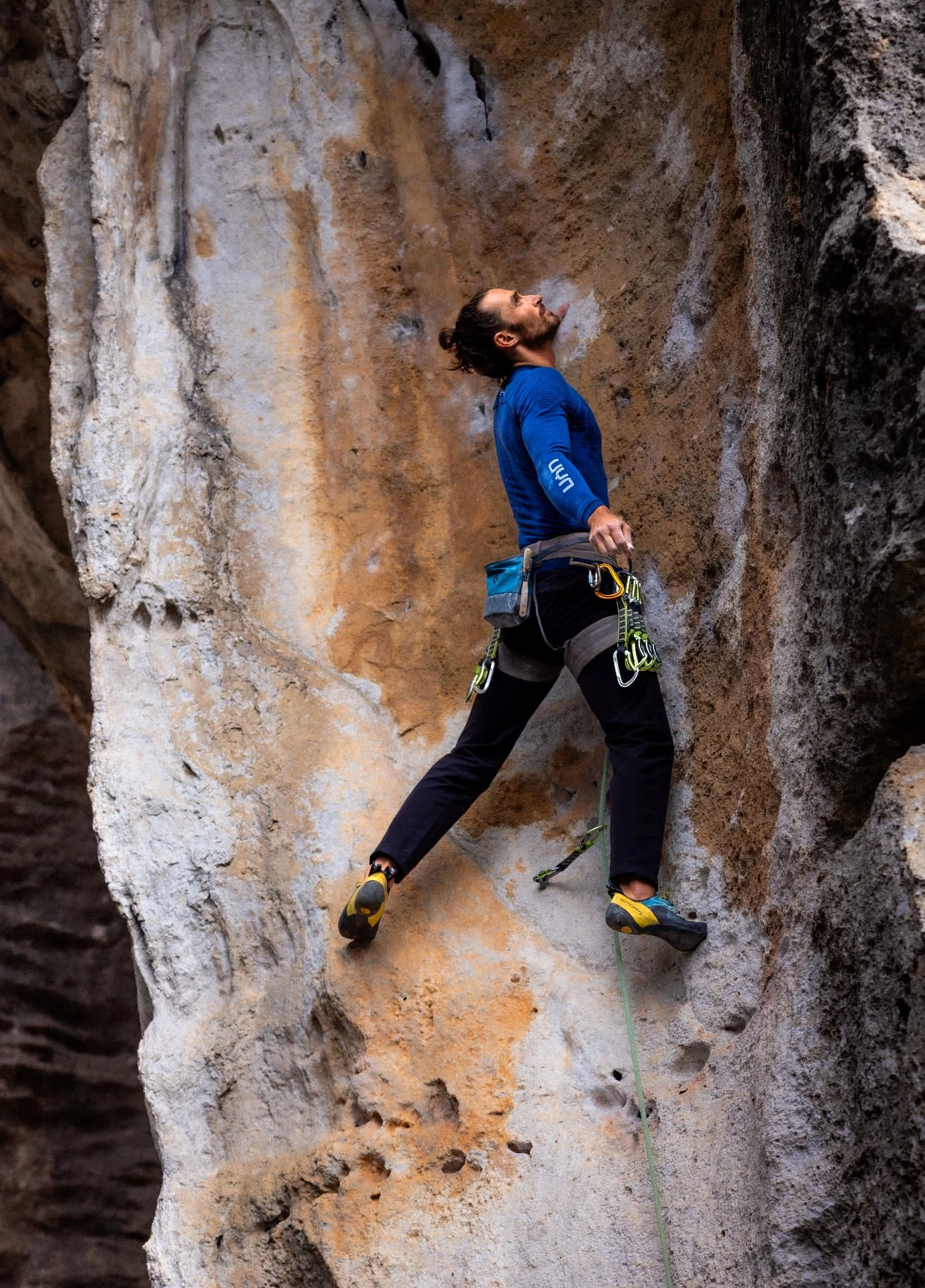 Climber in a blue shirt looking up on a textured limestone wall