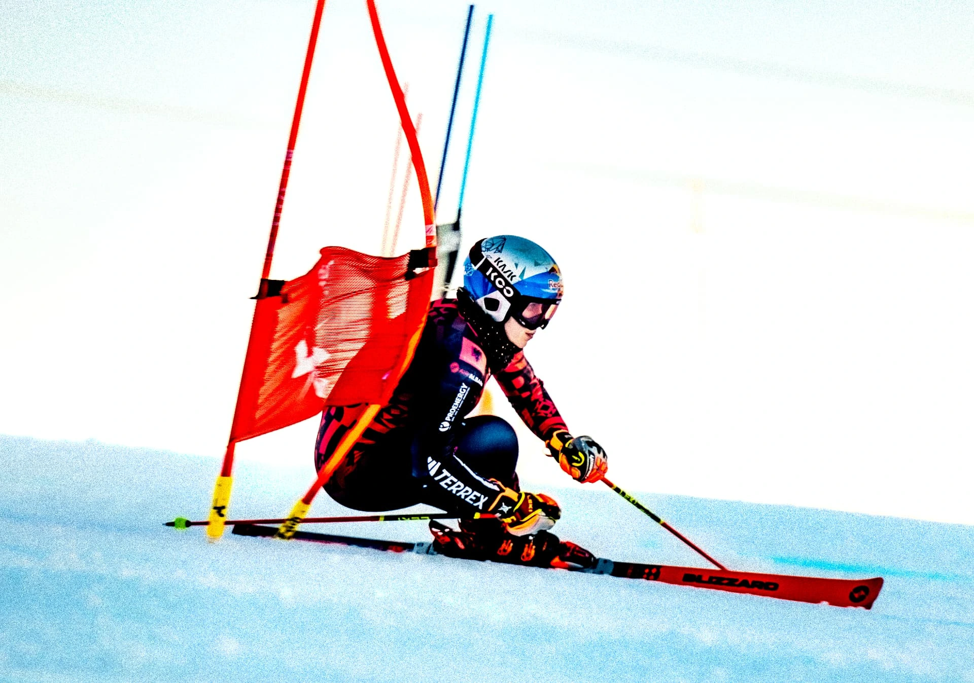 Ski racer leaning into a red gate at full speed
