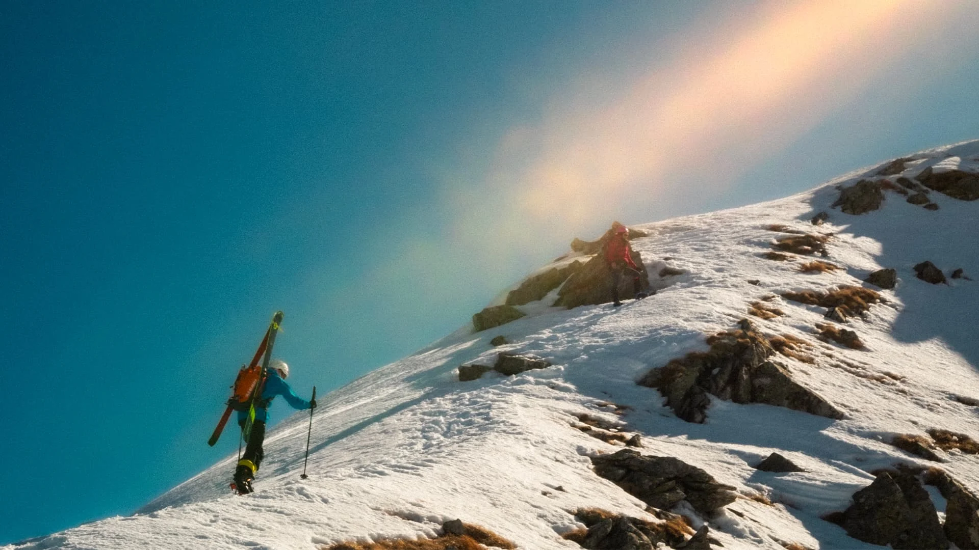 Ski mountaineers ascending a sunlit snowy ridge
