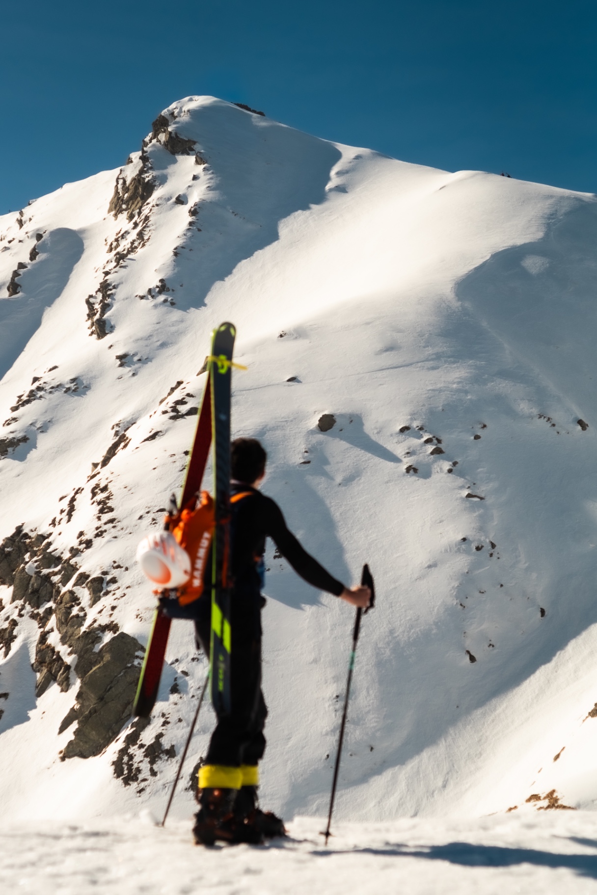 Ski tourer with skis on the backpack eyeing the ridge to climb