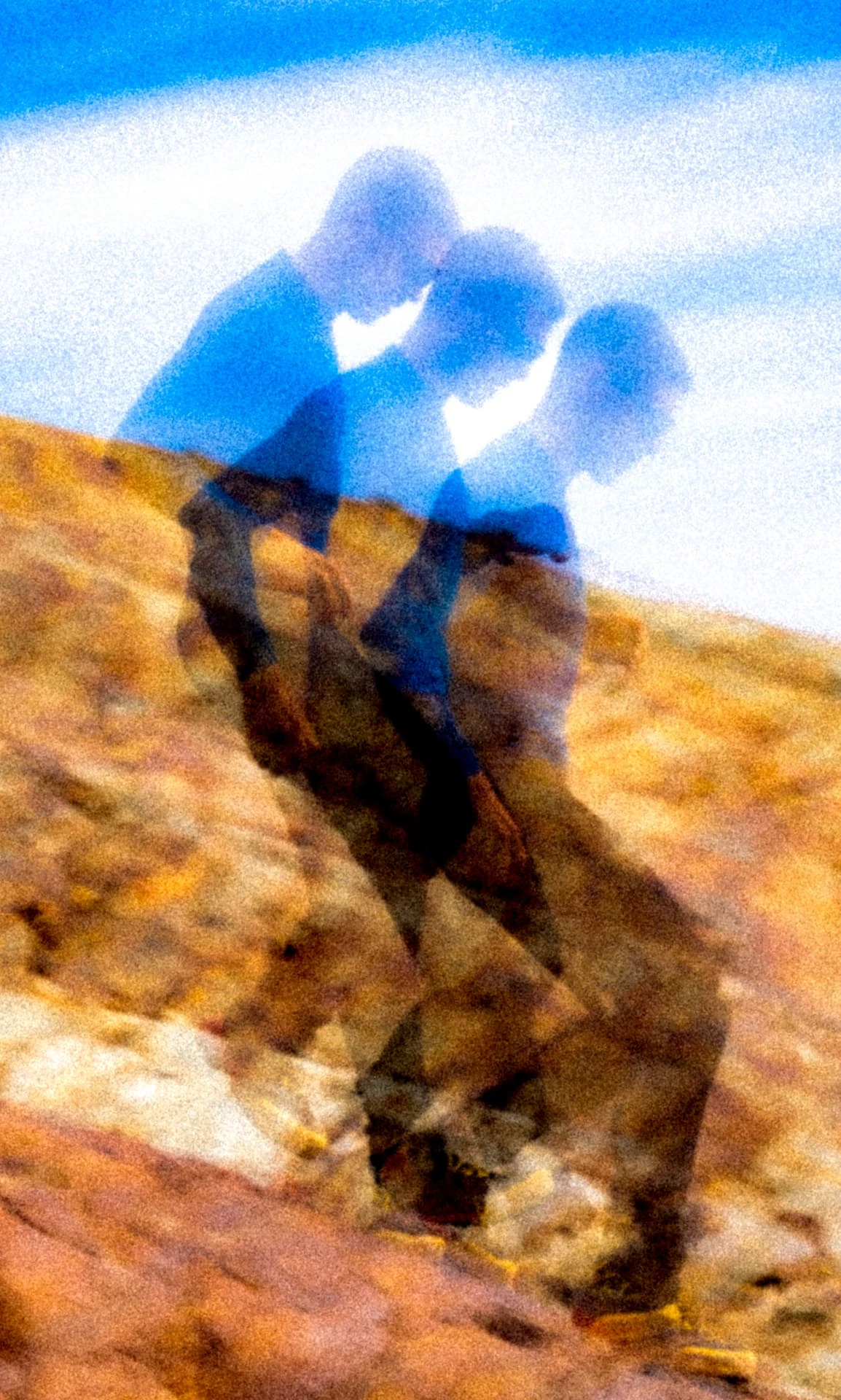 Double exposure of a climber walking over golden rock against a blue sky