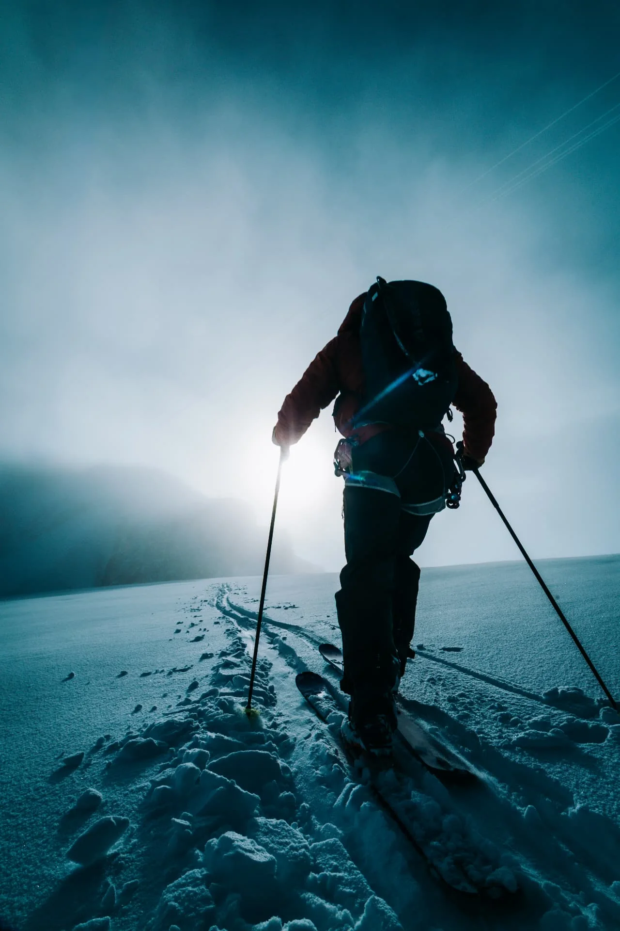 Ski mountaineer climbing toward the light on a snowy slope