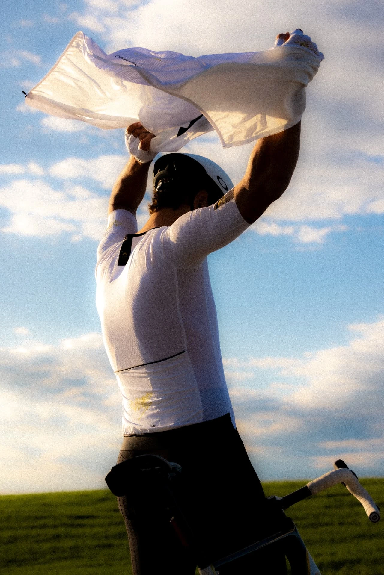 Cyclist taking off his white jersey backlit in the countryside
