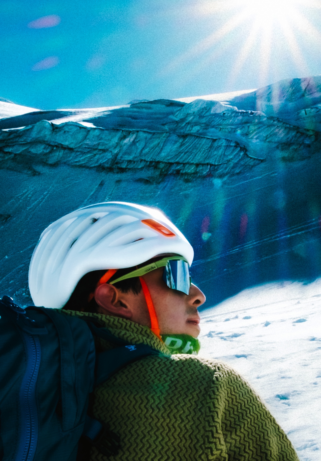 Portrait of an alpinist with helmet and goggles in front of a glacier