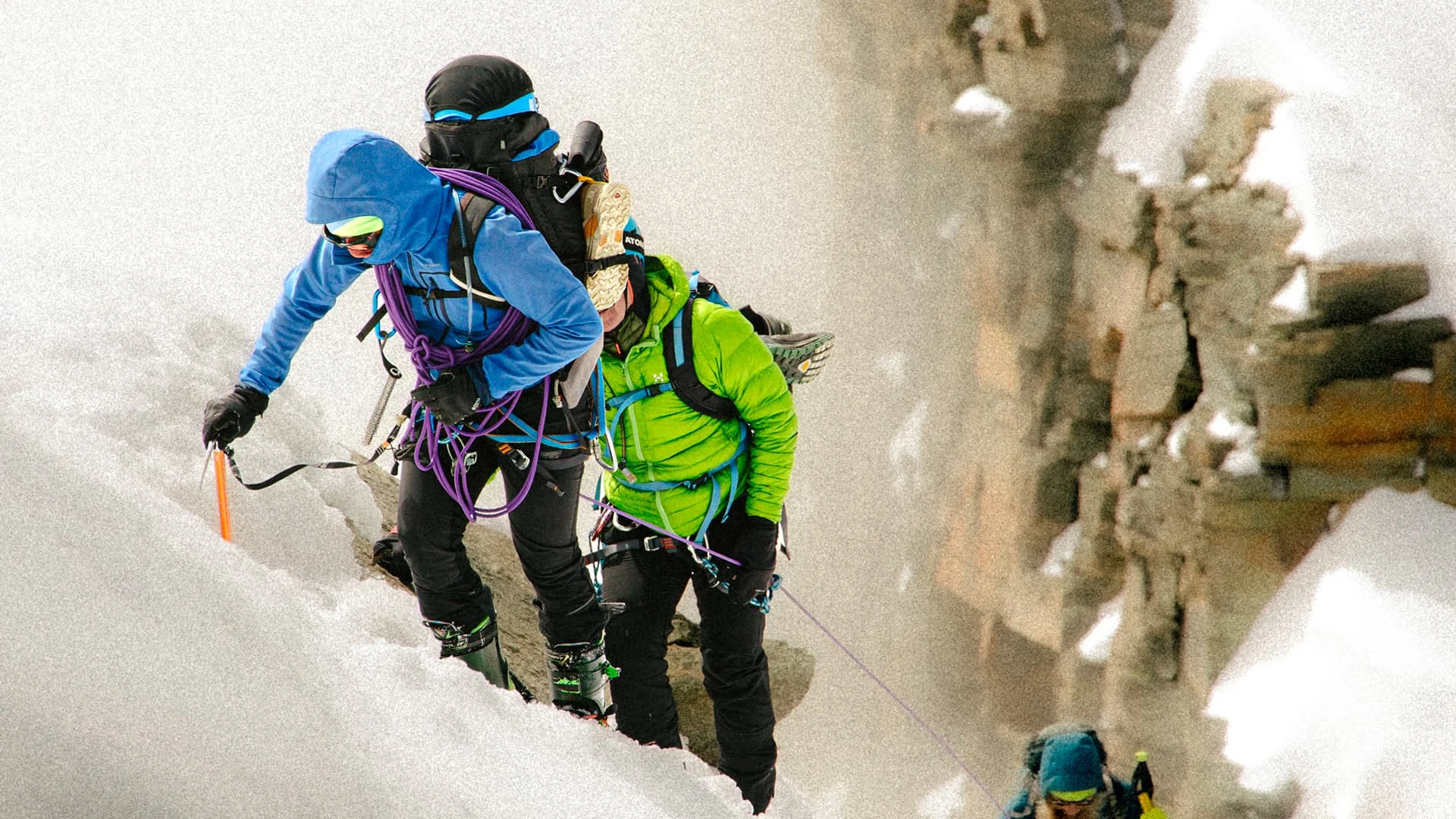 Roped alpinists traversing a steep snowy mountain face