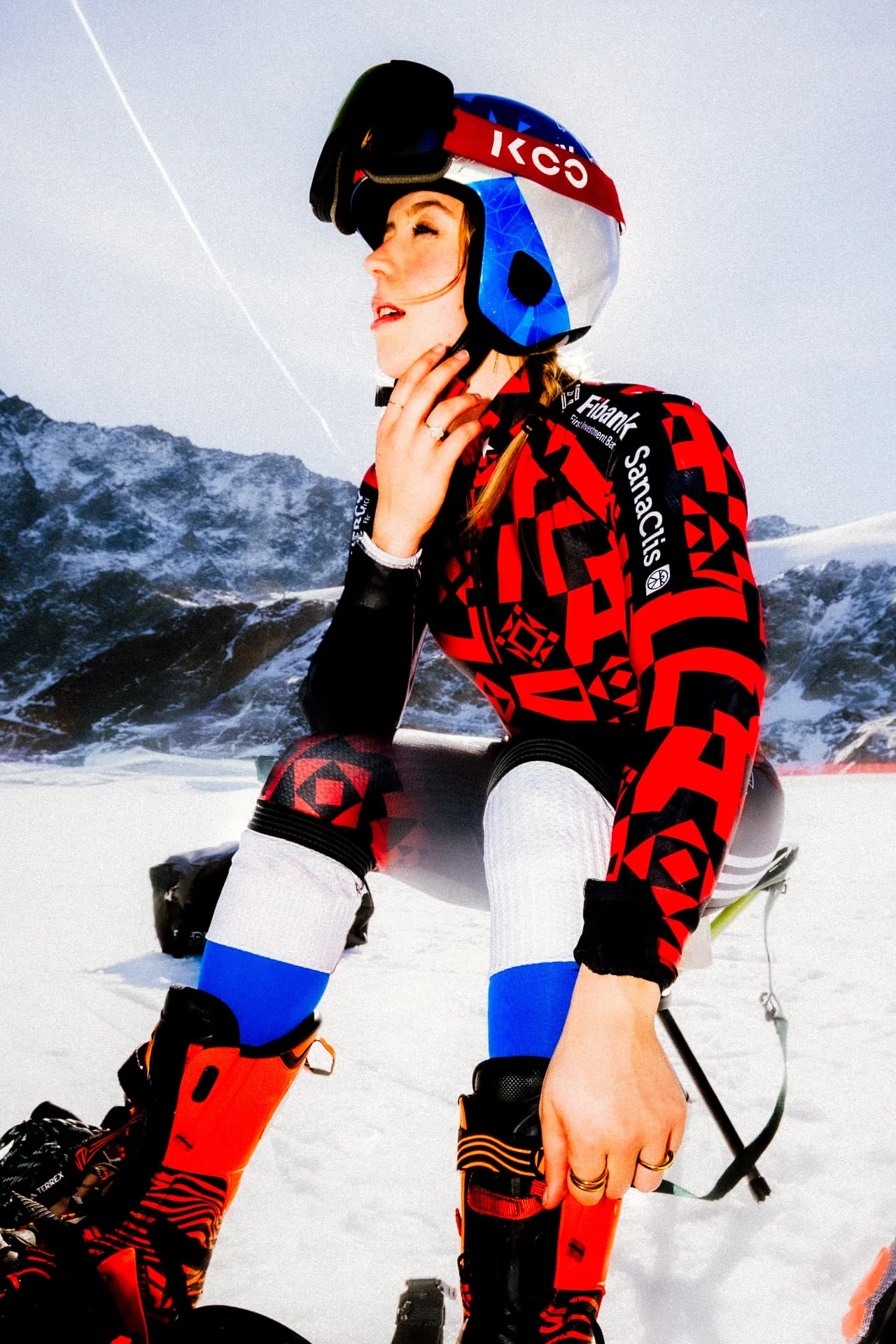 Ski racer kneeling on the snow, profile with helmet and goggles up