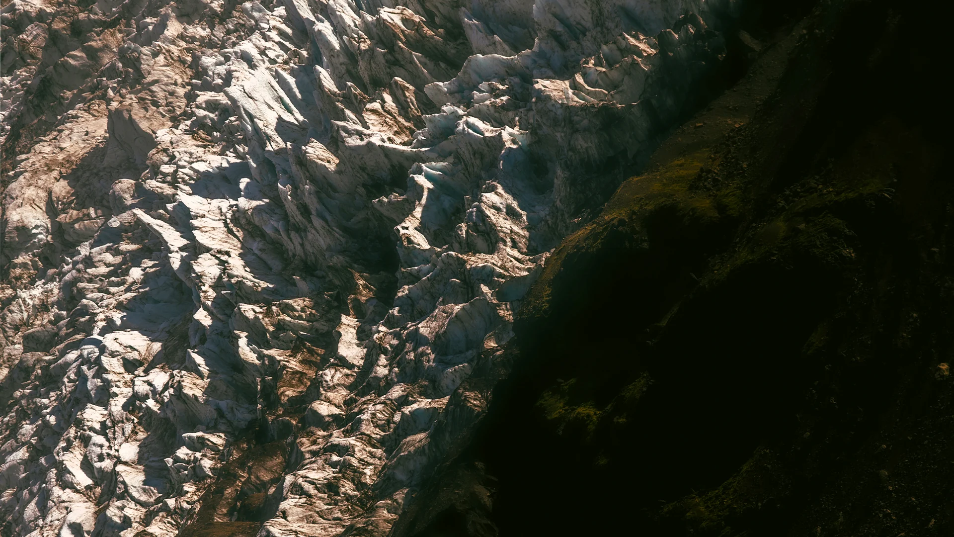 Abstract contrast between a sunlit glacier and a dark mountainside