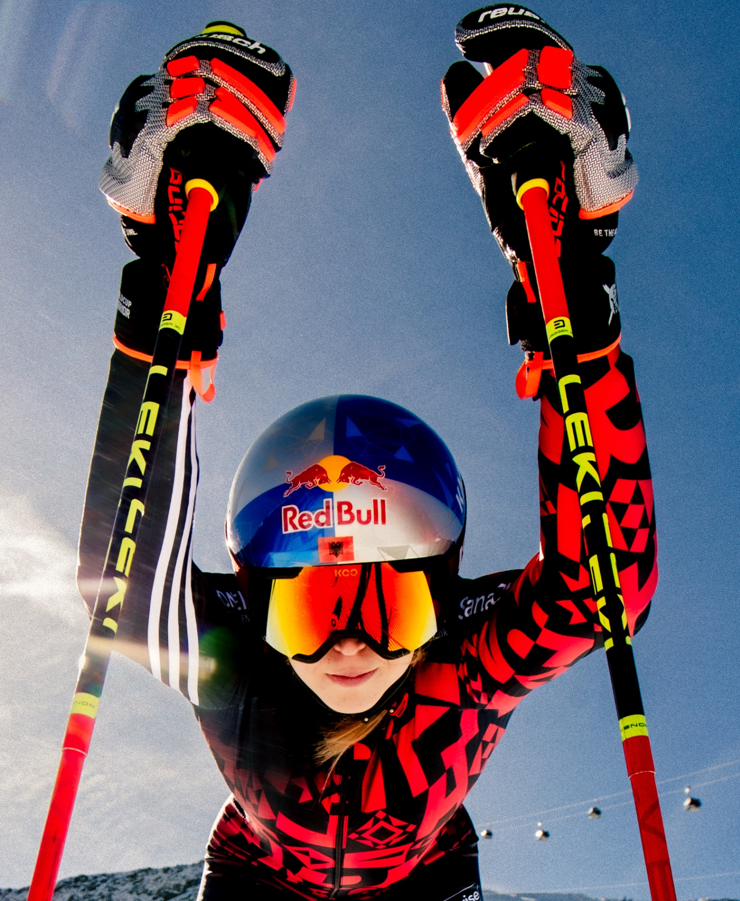 Skier in a red race suit with Red Bull helmet, poles raised