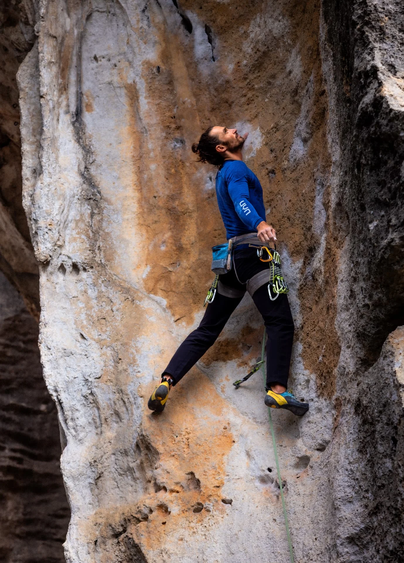 Climber in a blue shirt looking up on a textured limestone wall