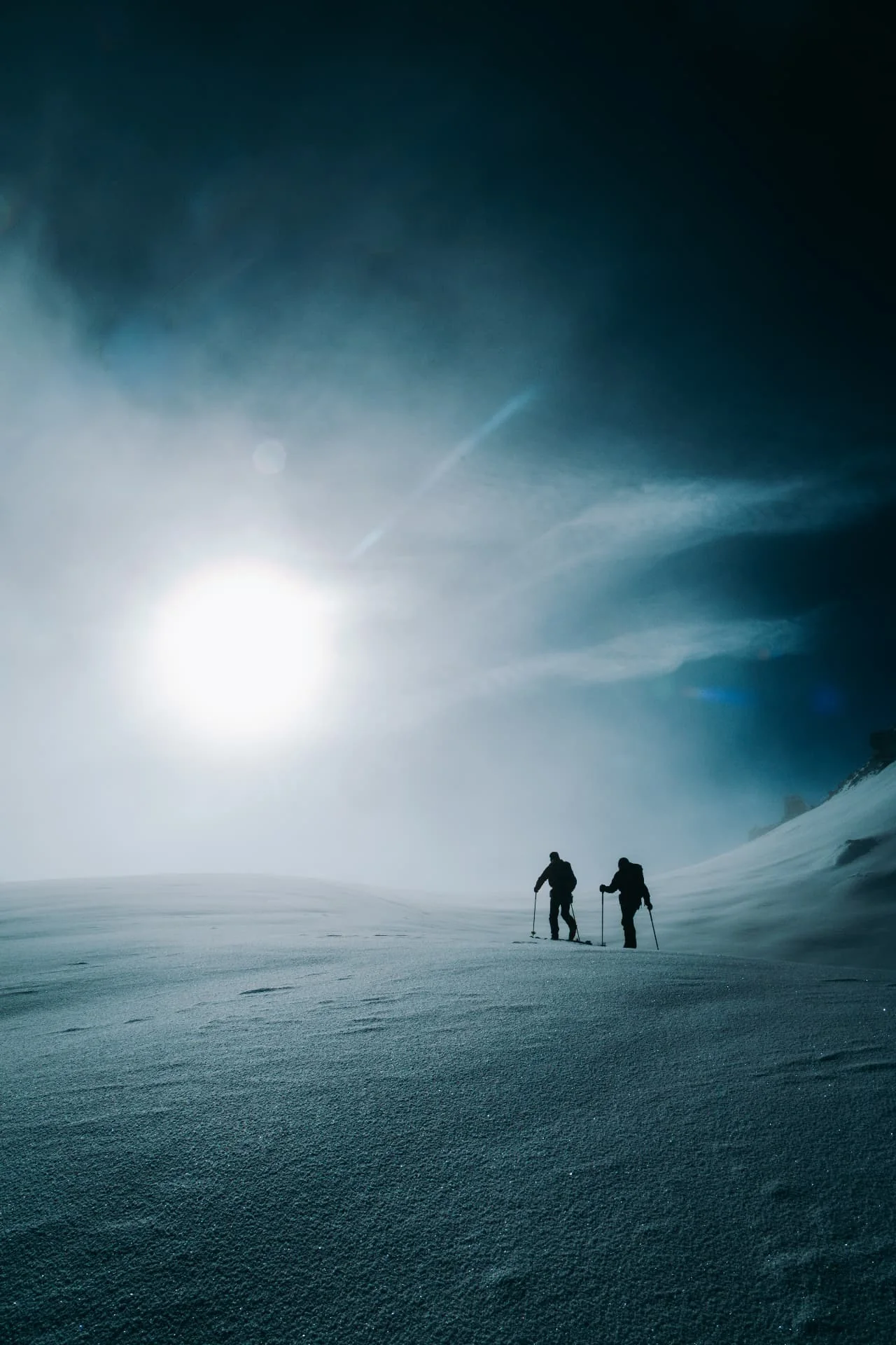 Two ski mountaineers crossing a broad snowy landscape