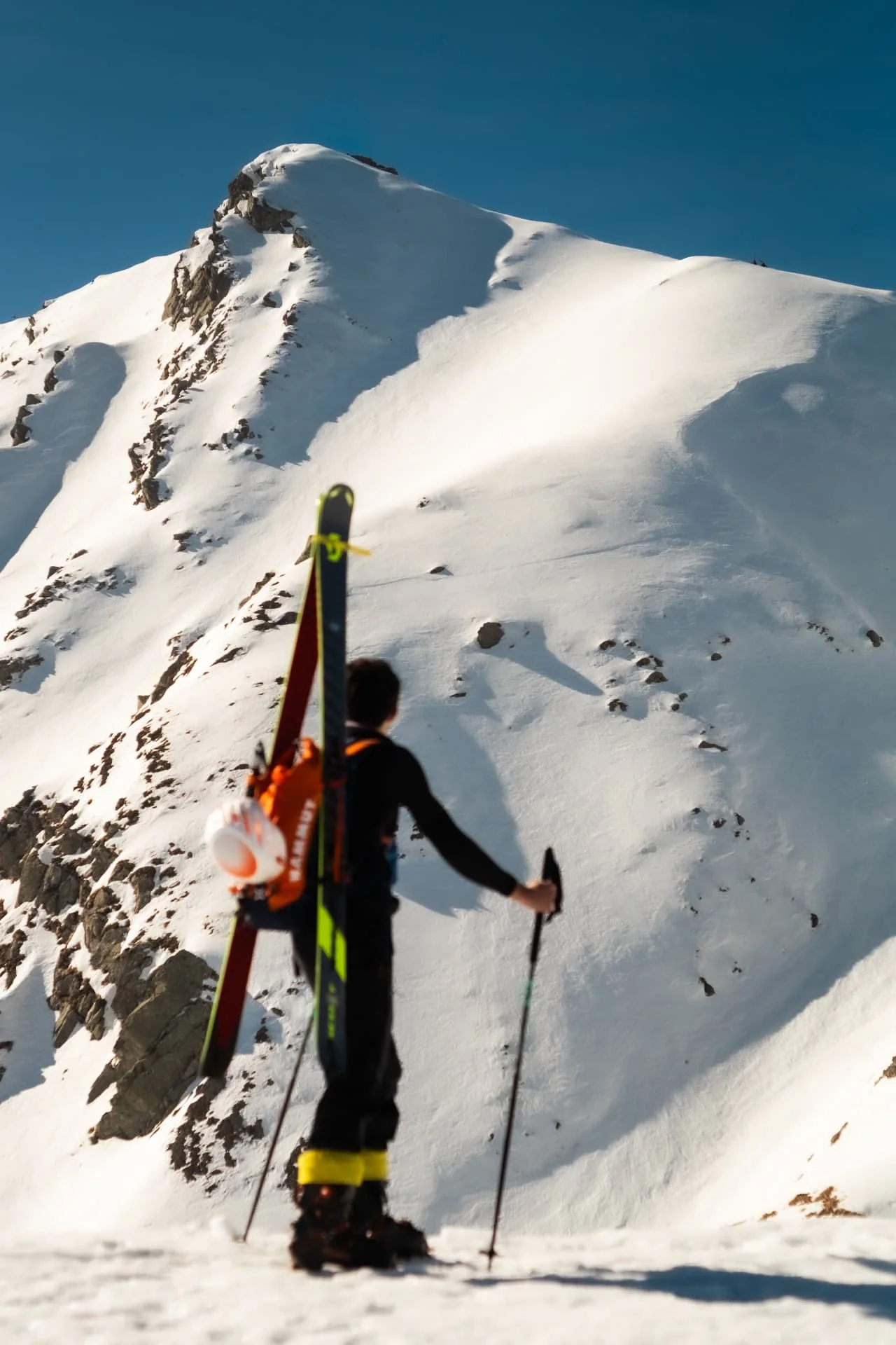 Ski mountaineer approaching a steep snow-covered peak