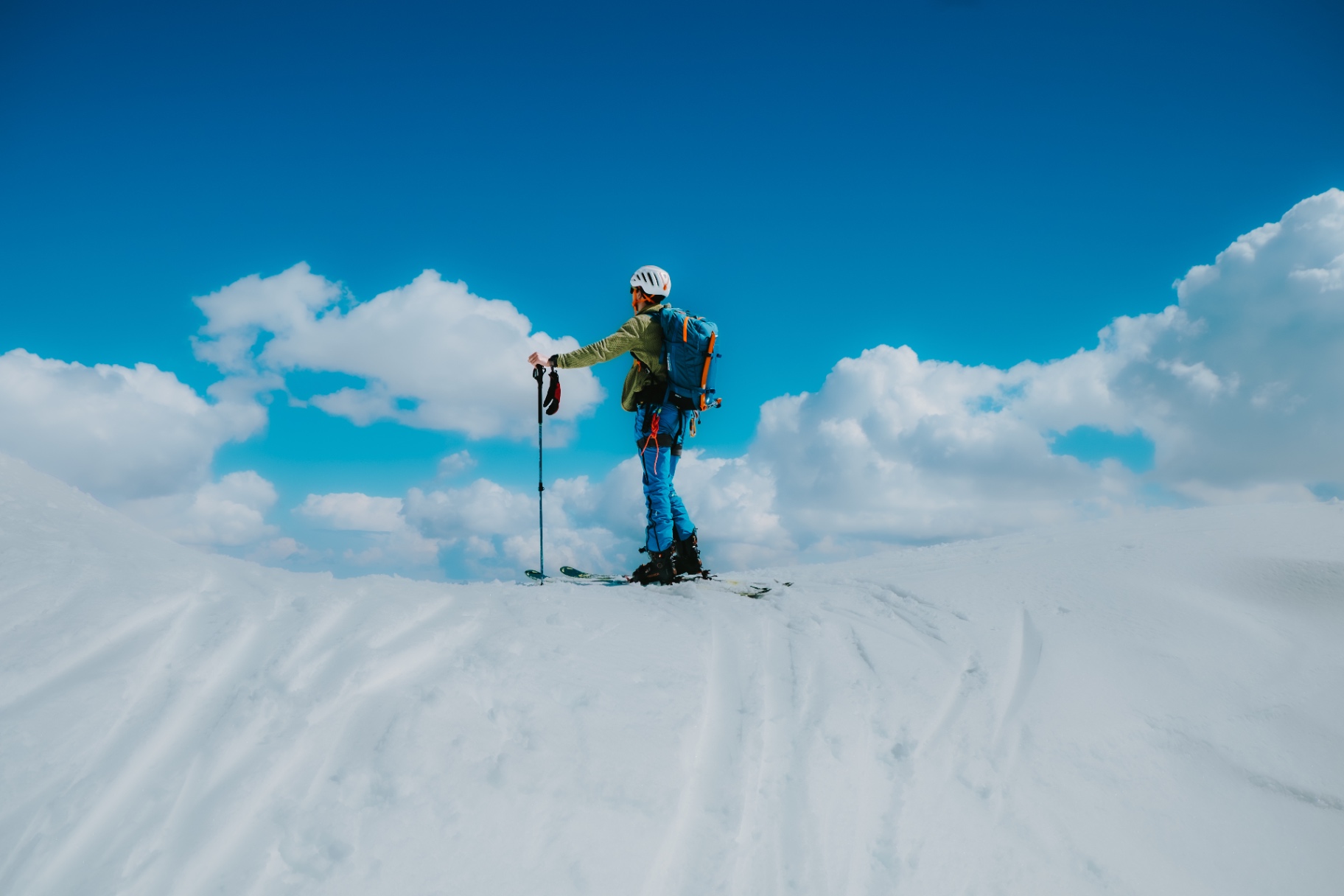 Ski tourer on the summit with a sea of clouds on the horizon