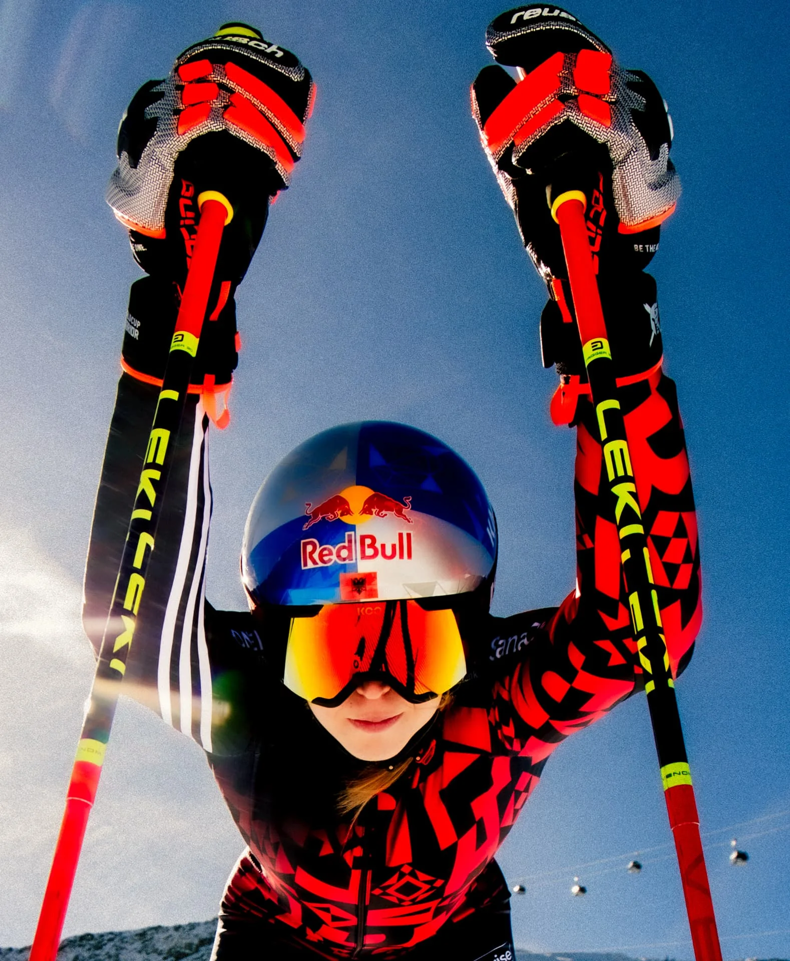 Ski racer raising both poles toward the camera